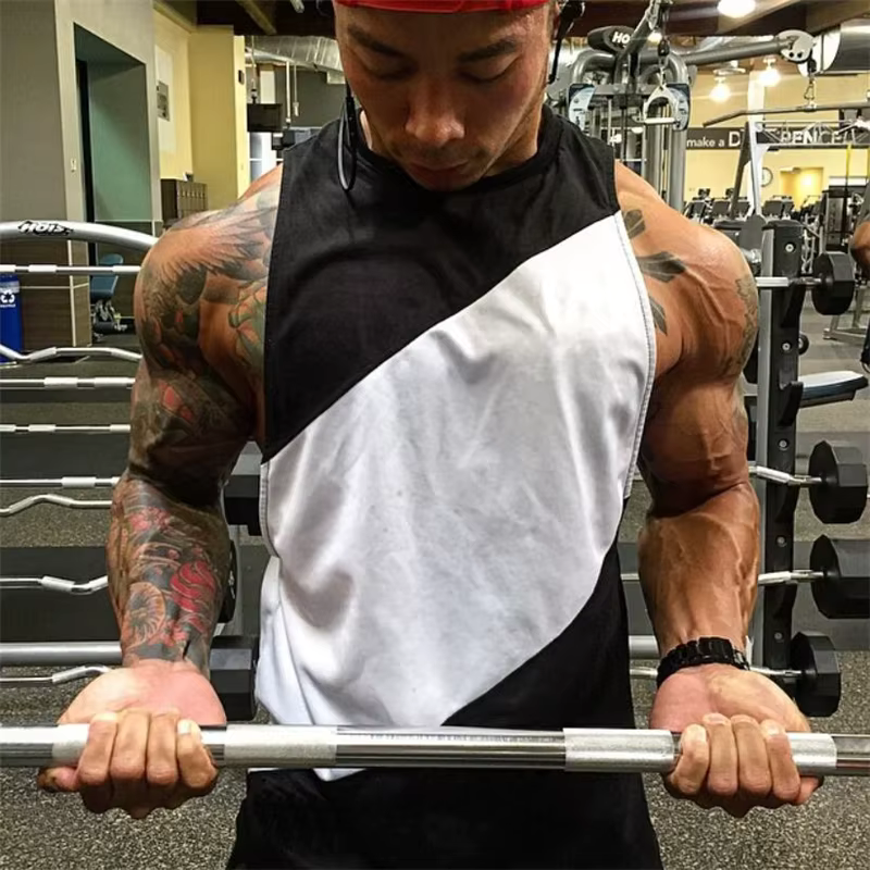 Man lifting a barbell in a sleeveless gym tank top, showcasing strength and fitness in a training environment.