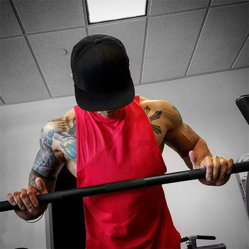 Man in red mesh cotton gym tank top lifting weights, showcasing muscle definition and strength training in the gym.
