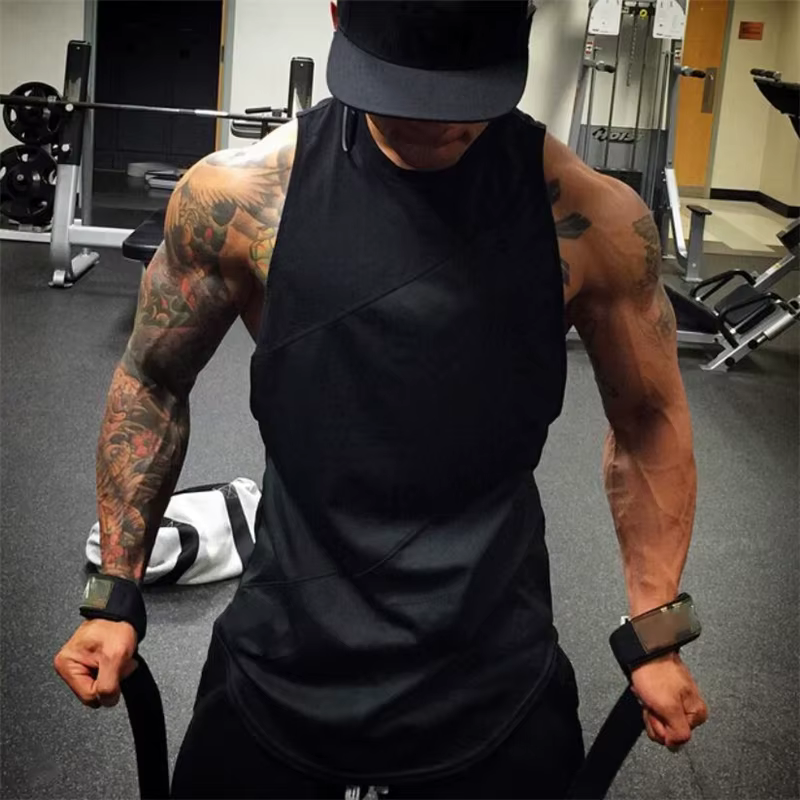 Muscular man wearing a black sleeveless mesh gym tank top in a fitness setting, showcasing strength and workout intensity.