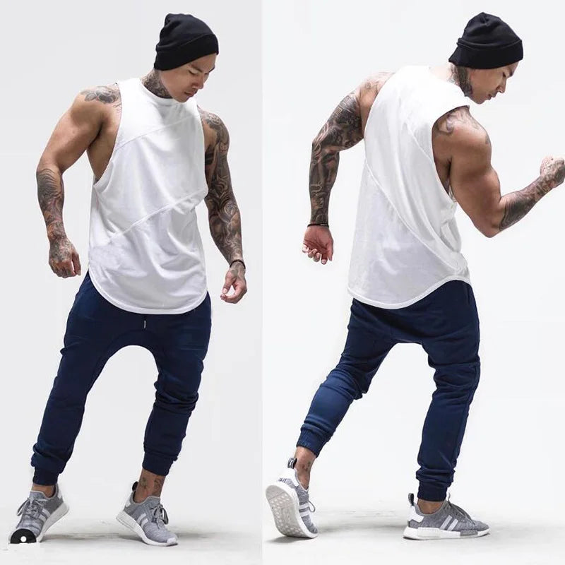Male model showcasing a sleeveless white gym tank top, paired with navy joggers, ideal for workouts and athletic activities.