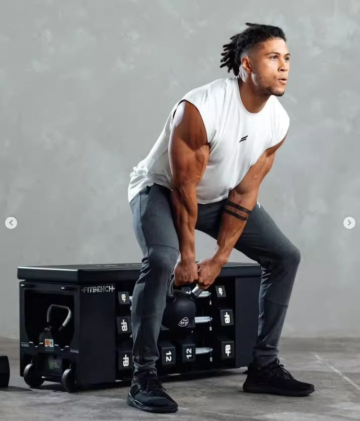 Man performing kettlebell exercise in gym with FITBENCH weights, showcasing strength and athleticism in workout gear.