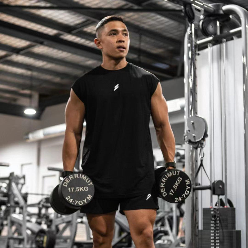 Man lifting weights in a gym wearing a black fitness tank top and shorts, demonstrating strength training.