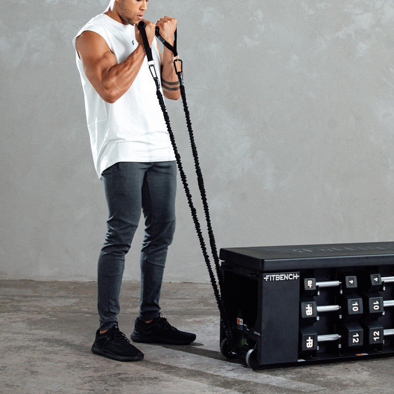 Man using resistance bands with a FITBENCH during a workout in a gym setting.