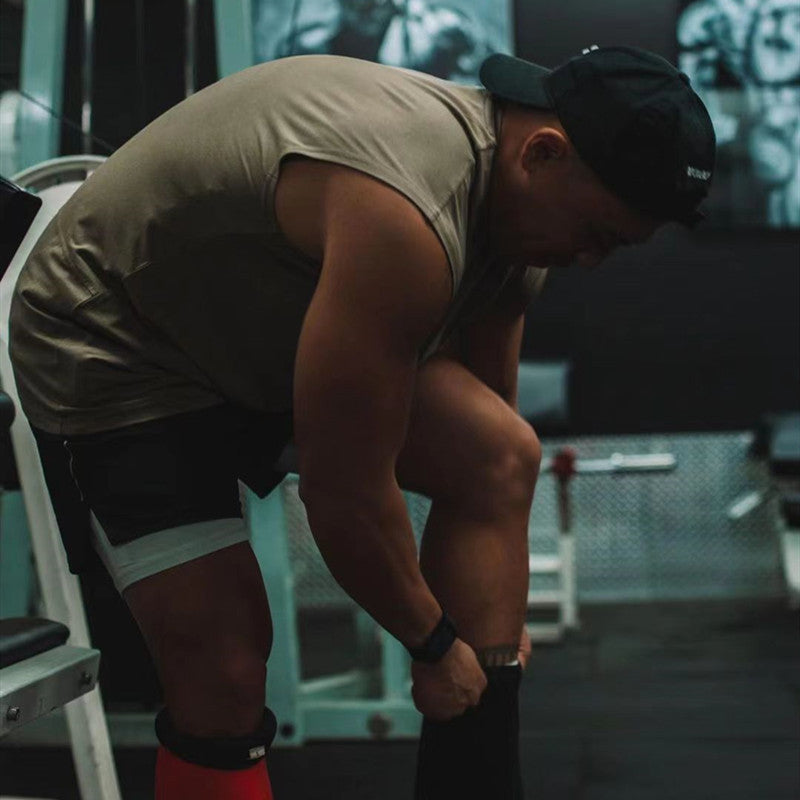 Man adjusting workout leg sleeves in a gym, showcasing fitness and summer sports attire.