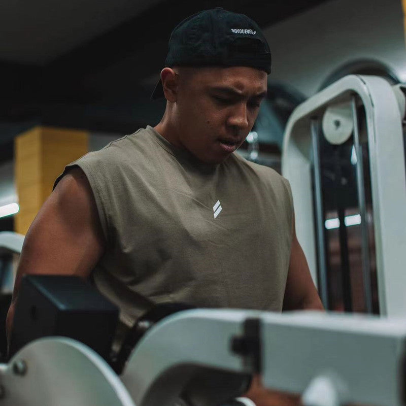 Man wearing a summer fitness sports tank top, focused on his workout in a modern gym environment.