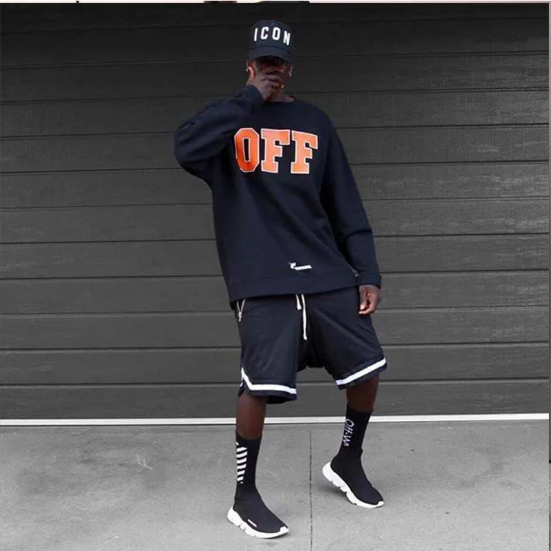 Stylish man in black basketball shorts and sweatshirt, showcasing athletic wear with a sporty vibe.