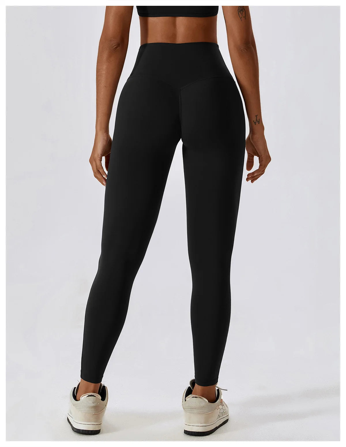 Back view of a woman wearing high-waist scrunch butt yoga leggings in black, showcasing the curve-enhancing design.