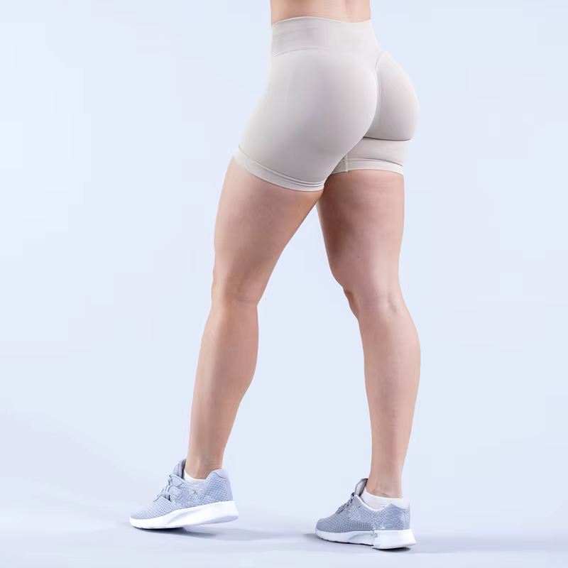 Woman wearing beige Gym Impact Running Shorts, showcasing a fitted design for workouts and athletic activities.