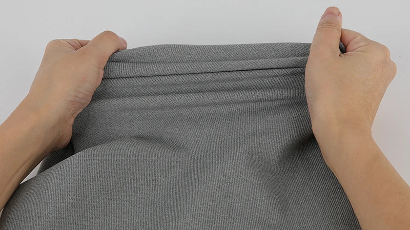 Hands holding the fabric of a men's compression tank top, showcasing its flexible material and design.