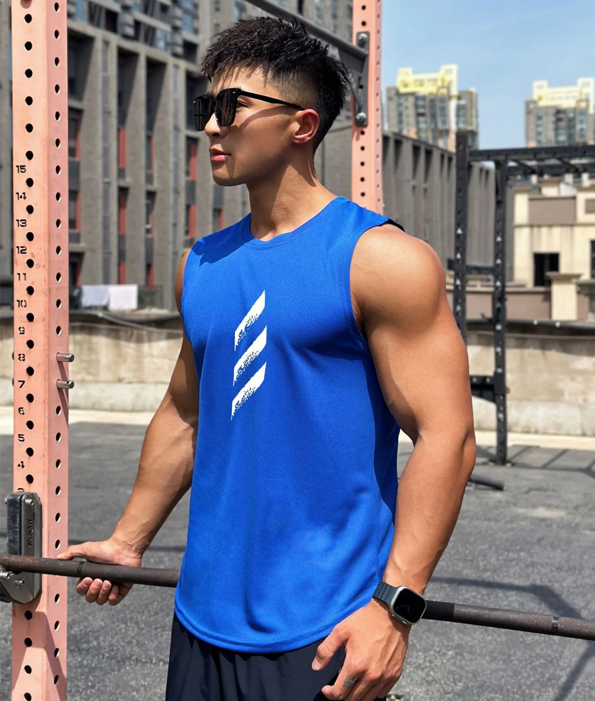 Young man wearing a blue quick-dry sleeveless gym tank top at an outdoor workout.