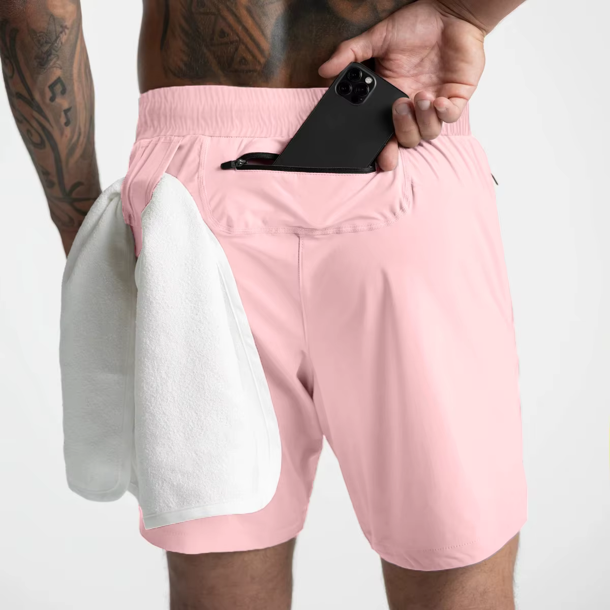 Man wearing pink lightweight gym shorts with a towel and phone in the back pocket, showcasing comfort and functionality.