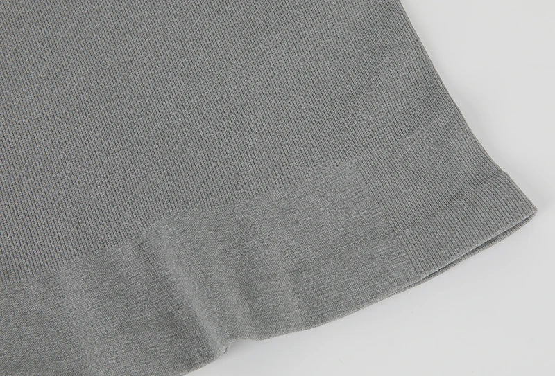 Detail of the hem of a men's gray compression tank top, showcasing the fabric texture and slim fit design.