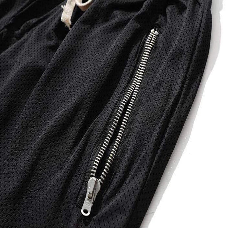 Close-up of black men's mesh basketball shorts with breathable fabric and zippered side pocket.