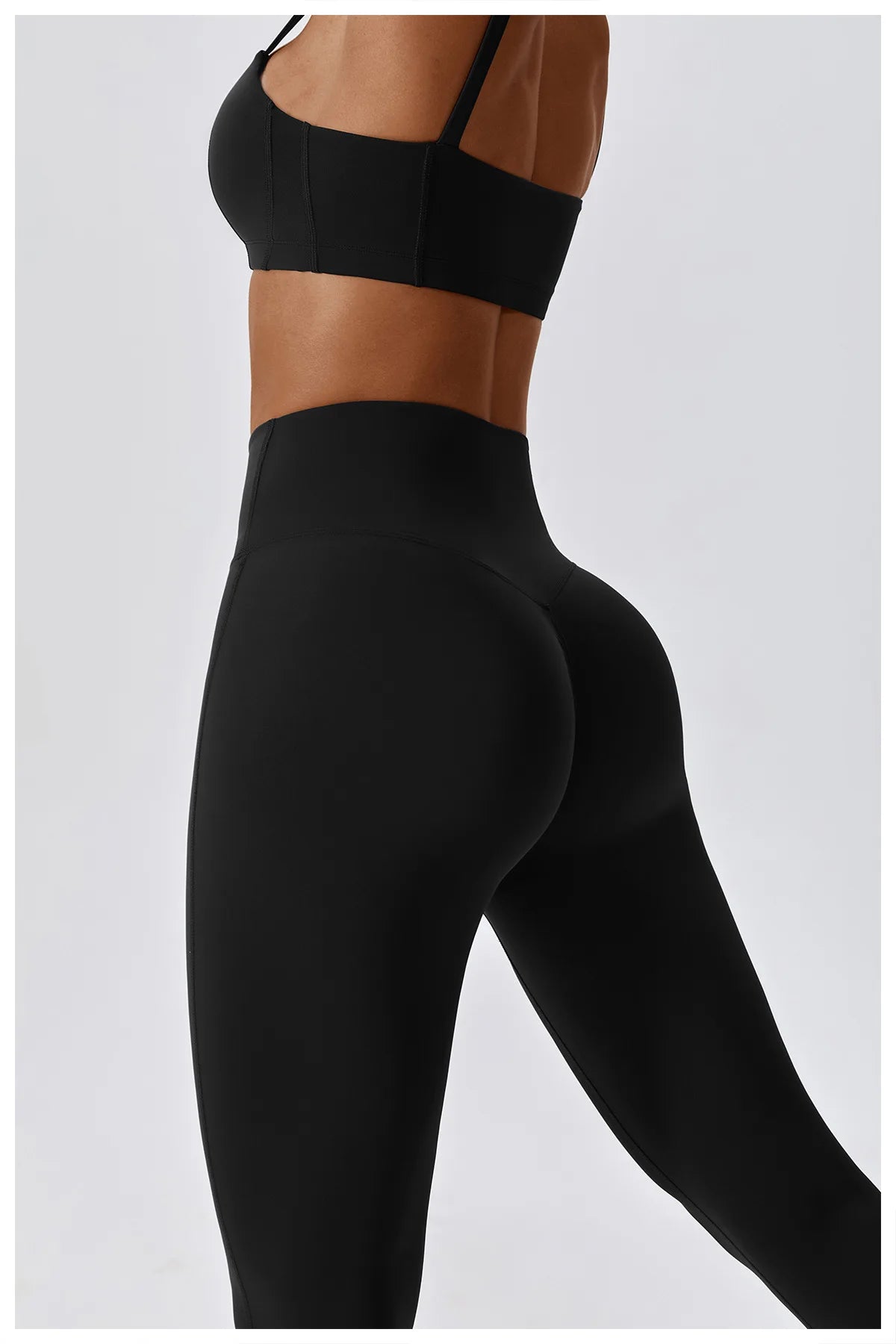 Side view of a woman wearing high-waist black scrunch butt yoga leggings, showcasing a flattering fit and style.