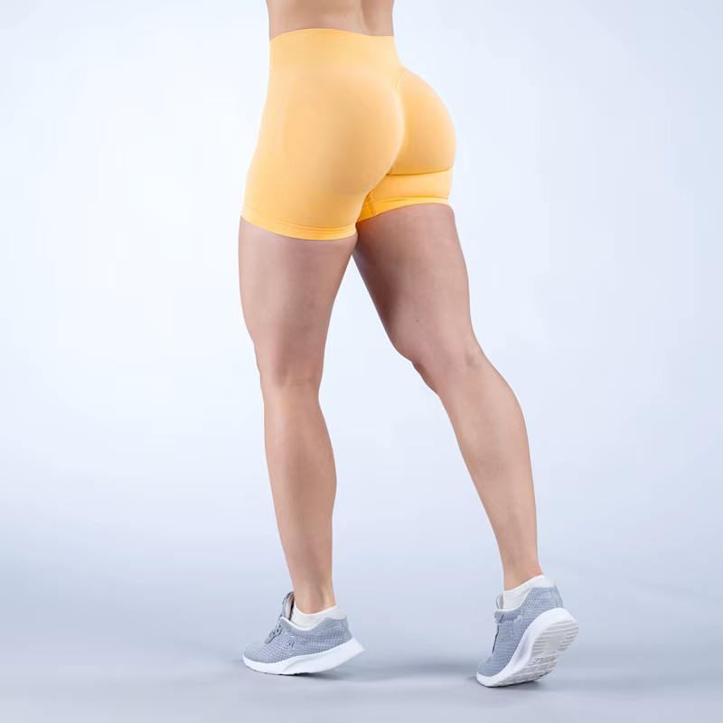 Female athlete wearing yellow Gym Impact Running Shorts from the back, showcasing style and fit for workouts.