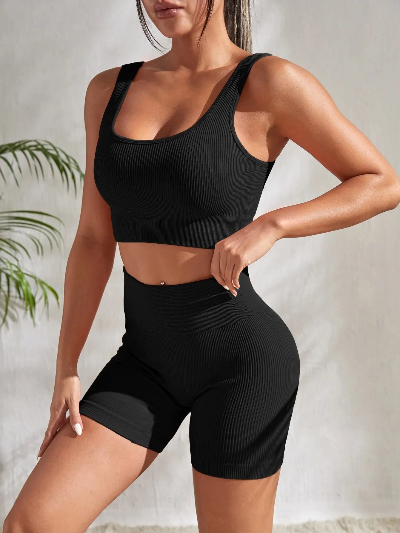 Model wearing Women's Seamless Ribbed Yoga Set in black, featuring a crop tank and high-waisted shorts.