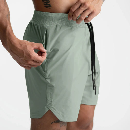 Men's lightweight gym shorts in soft green color, featuring an elastic waistband and side pocket for added convenience.