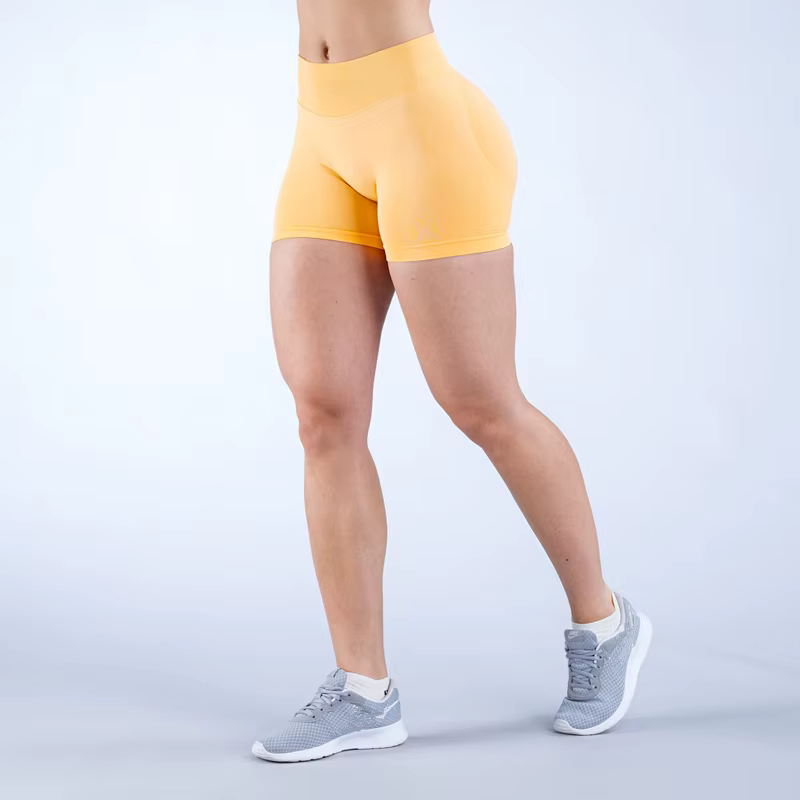 Legs of a person wearing yellow Gym Impact Running Shorts and gray sneakers, showcasing athletic style for workouts.