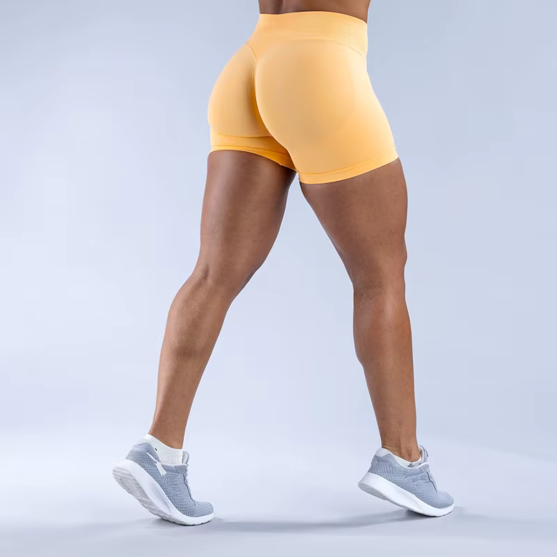 Woman wearing yellow Gym Impact Running Shorts from the back, showcasing sleek design and athletic style.