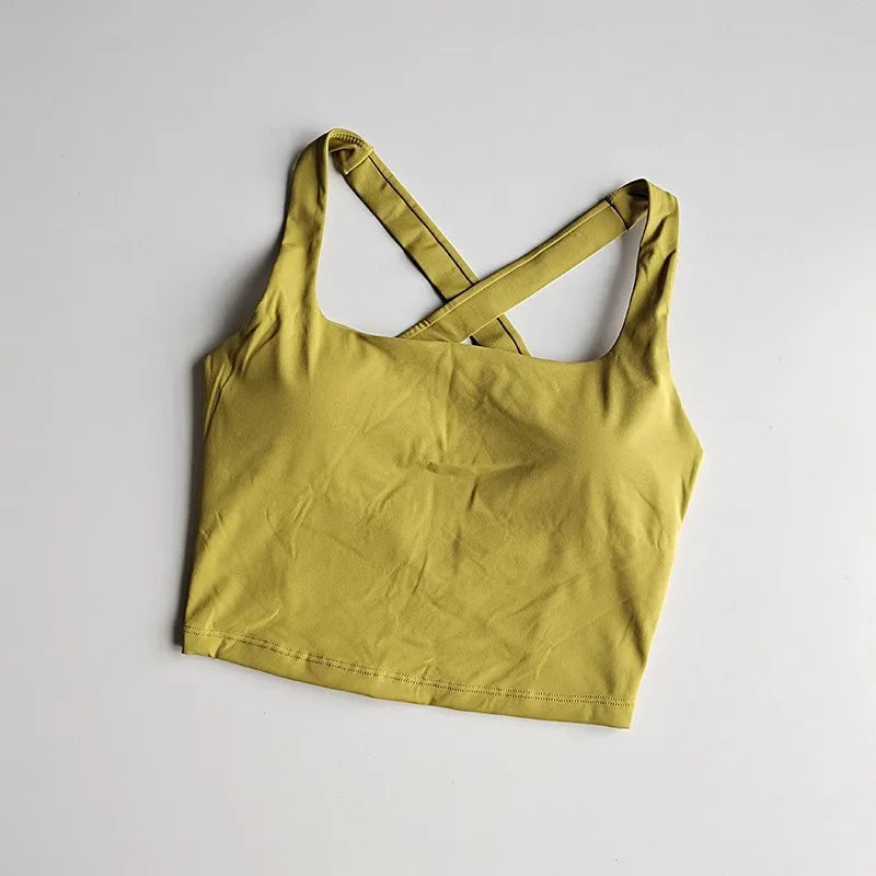 Seamless push-up sports bra for women in mustard yellow with crisscross straps and soft, breathable fabric.