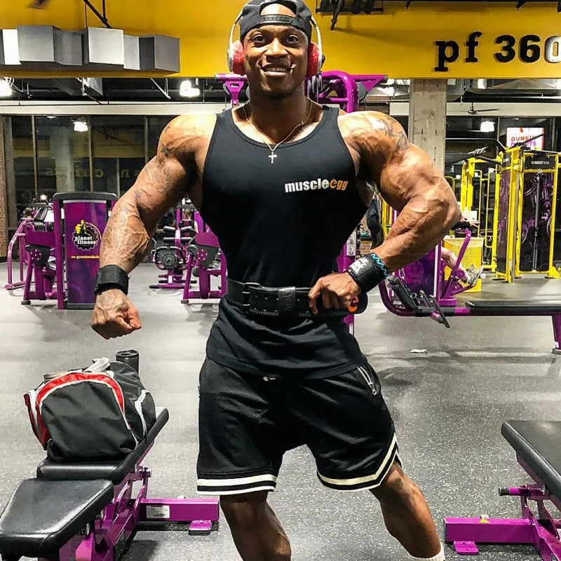 Muscular man wearing workout gear and headphones at the gym, showcasing strength and fitness.