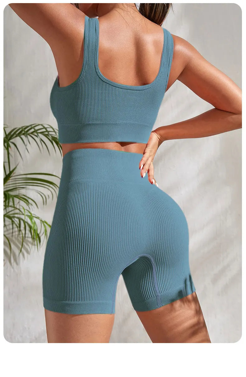 Back view of women's seamless ribbed yoga set in blue featuring crop tank and high-waisted shorts, perfect for workouts.