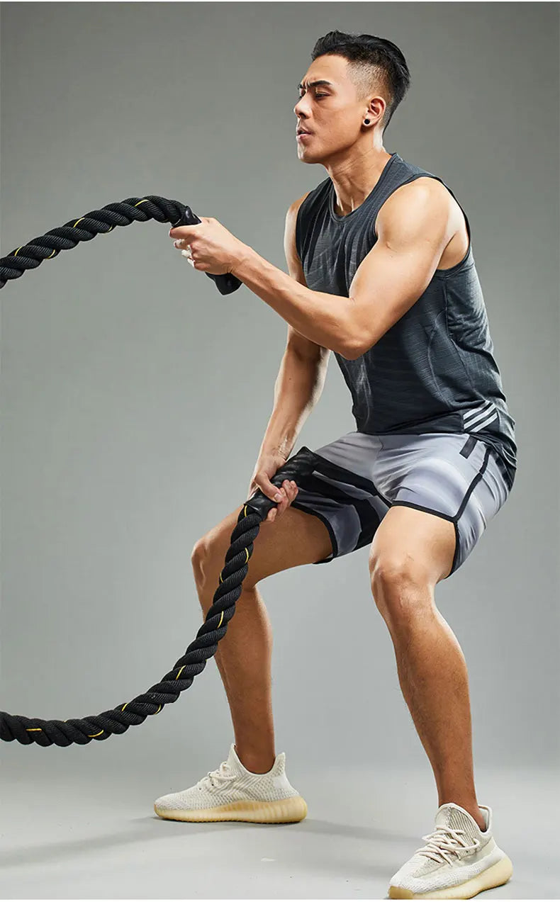 Fit man training with battle ropes in a lightweight ice silk tank top for summer workouts.