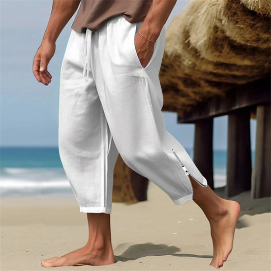 Man wearing white lightweight harem capri pants on the beach, perfect for casual and active wear.