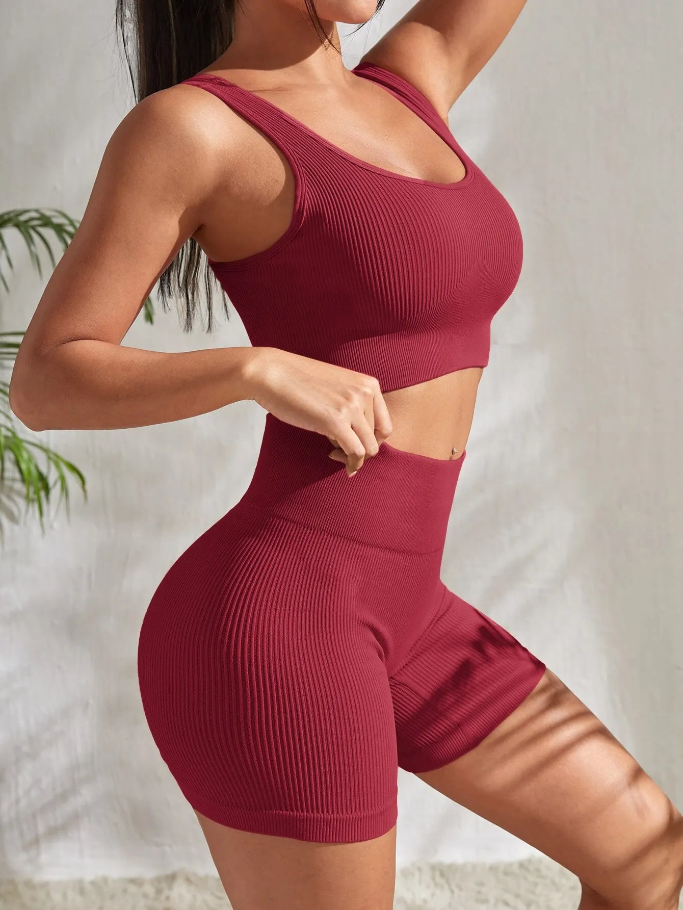 Women's seamless ribbed yoga set in burgundy featuring a crop tank top and high-waisted shorts.