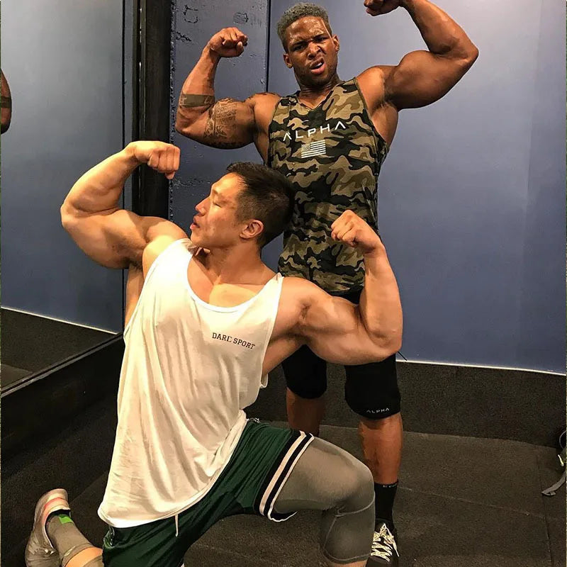 Two muscular men flexing in a gym, showcasing strength and fitness while dressed in athletic wear.