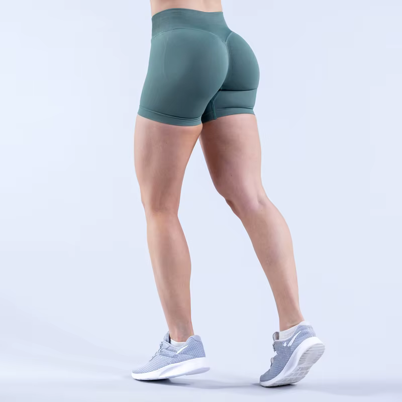 Woman wearing green Gym Impact Running Shorts showcasing form-fitting design and athletic shoes.