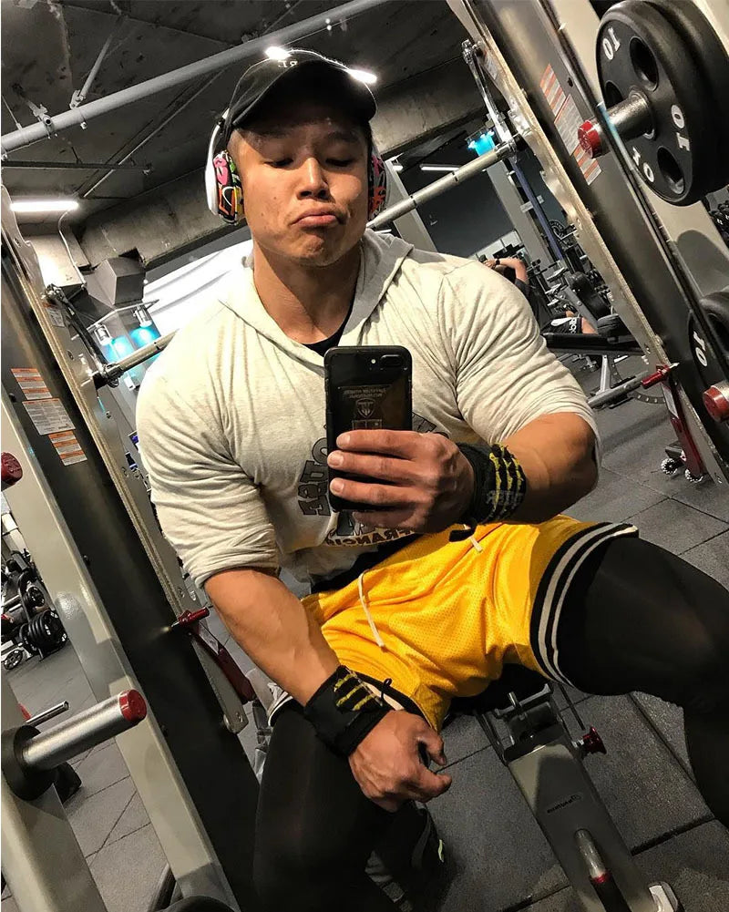 Man in gym attire taking a mirror selfie while working out, showcasing dedication and fitness lifestyle.
