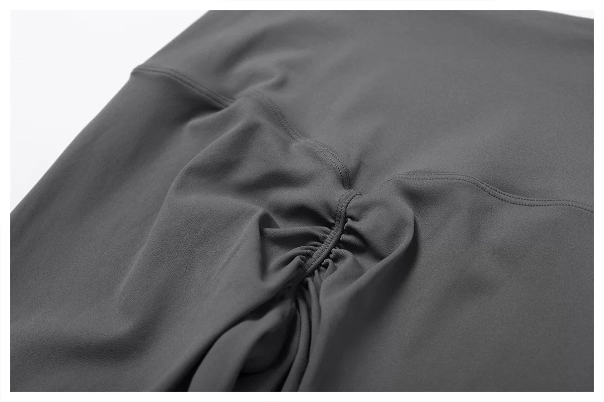 Close-up of high-waist scrunch butt yoga leggings in dark gray fabric showcasing the push-up seam detail.