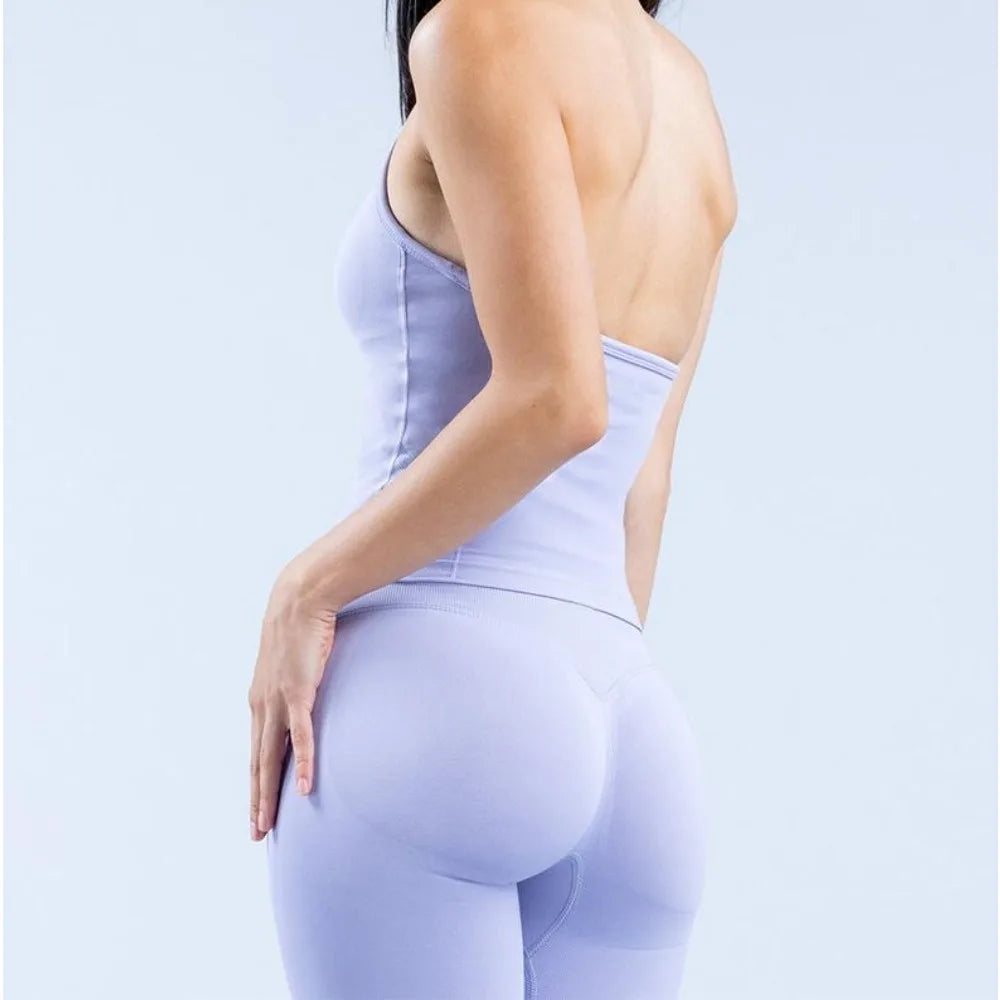 Back view of a woman wearing a light purple strappy V-neck yoga fitness top and matching leggings.