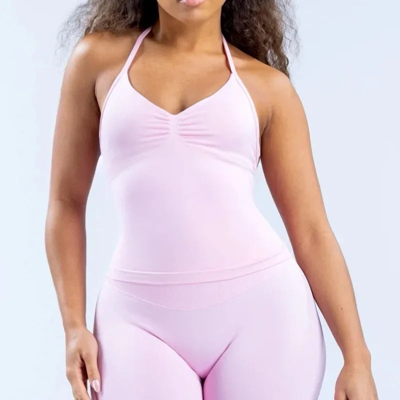 Women wearing a pink strappy V-neck workout top with open-back design, perfect for yoga and fitness activities.