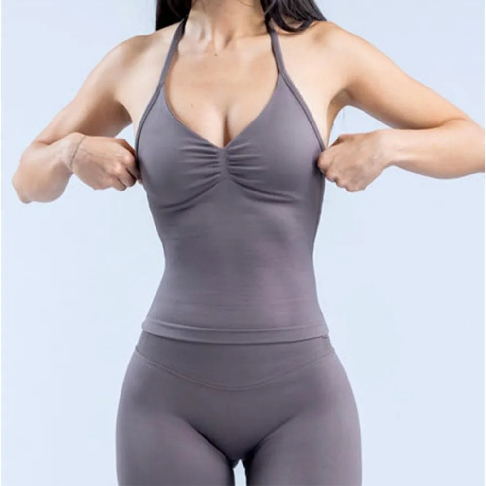 Woman adjusting a strappy V-neck yoga top in gray, ideal for fitness and outdoor workouts.