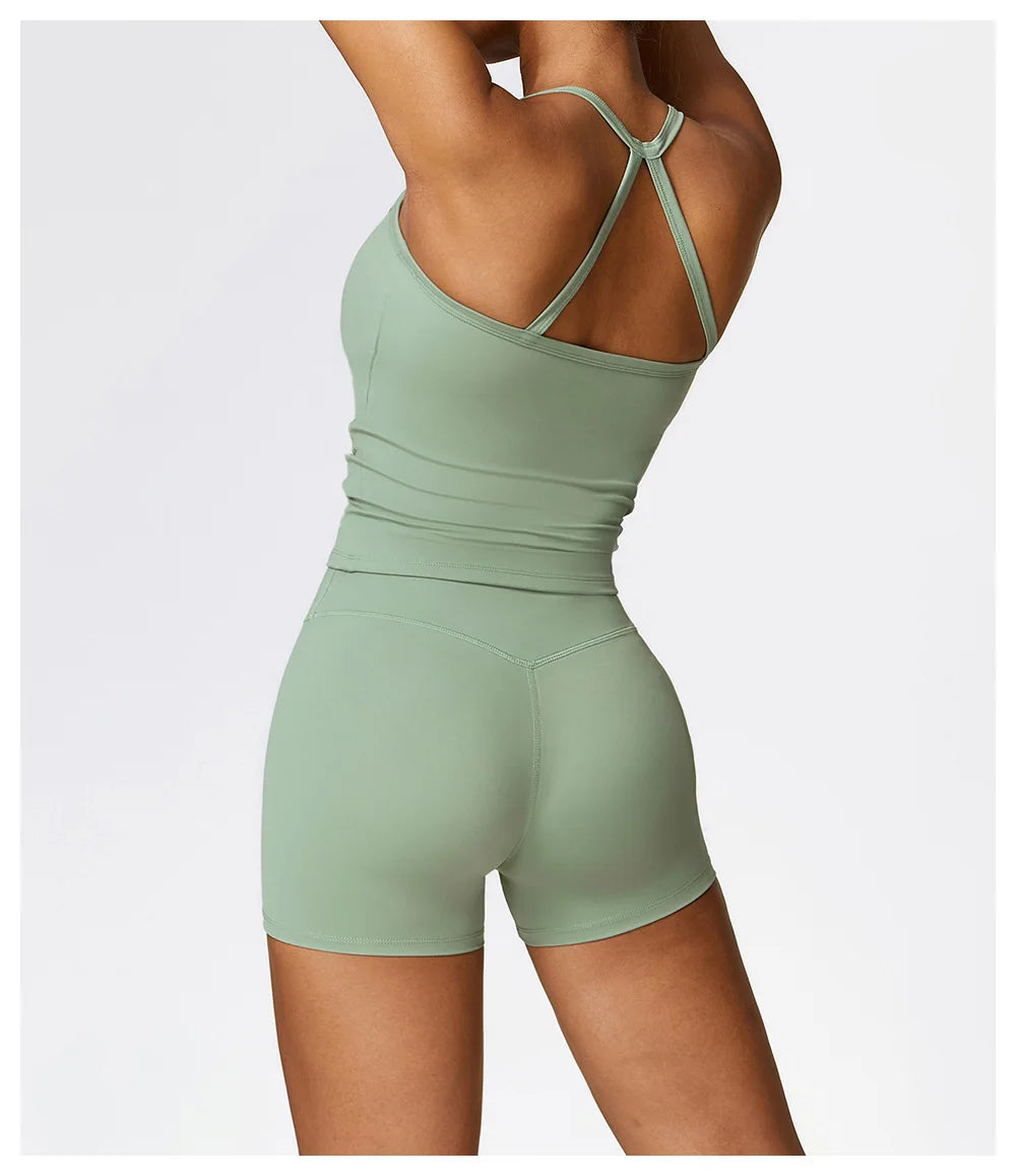 Back view of a woman wearing a green sports bra and shorts, showcasing the trendy cross-back design.