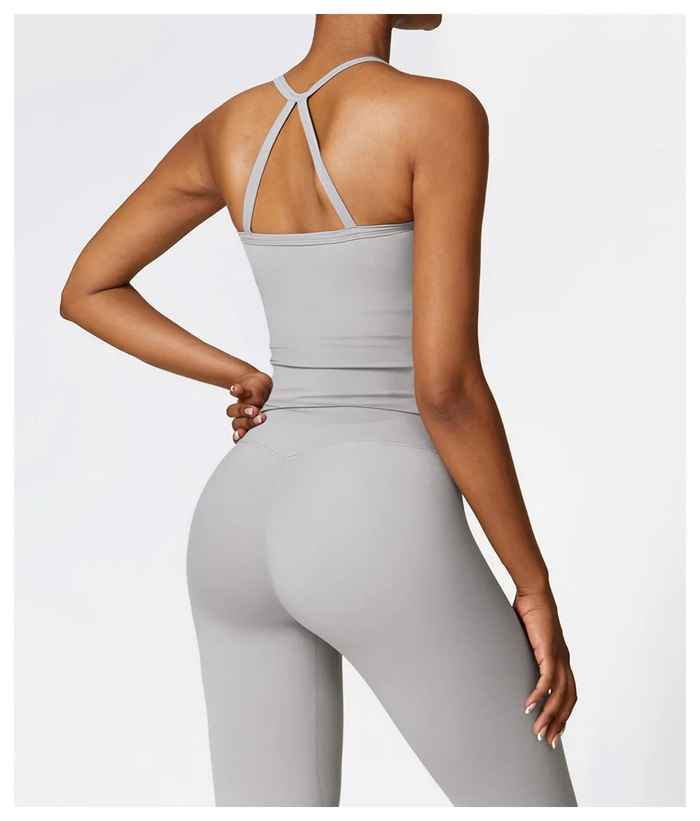Back view of a woman in a grey Cross Back Push-Up Sports Bra and high-waisted leggings, showcasing stylish activewear.