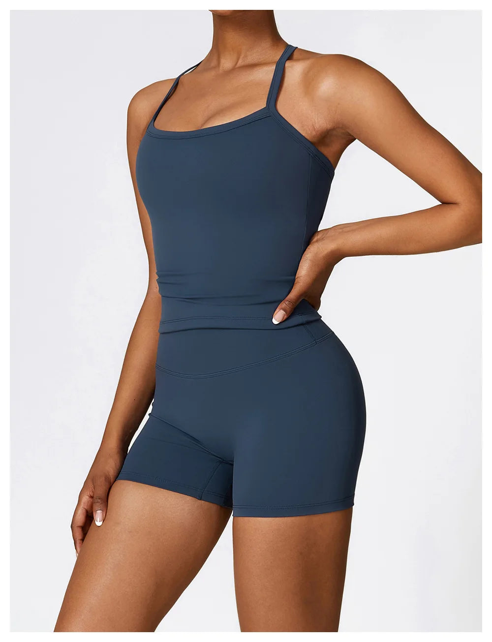Model wearing a dark blue cross-back sports bra and shorts, showcasing stylish athletic apparel for workouts.