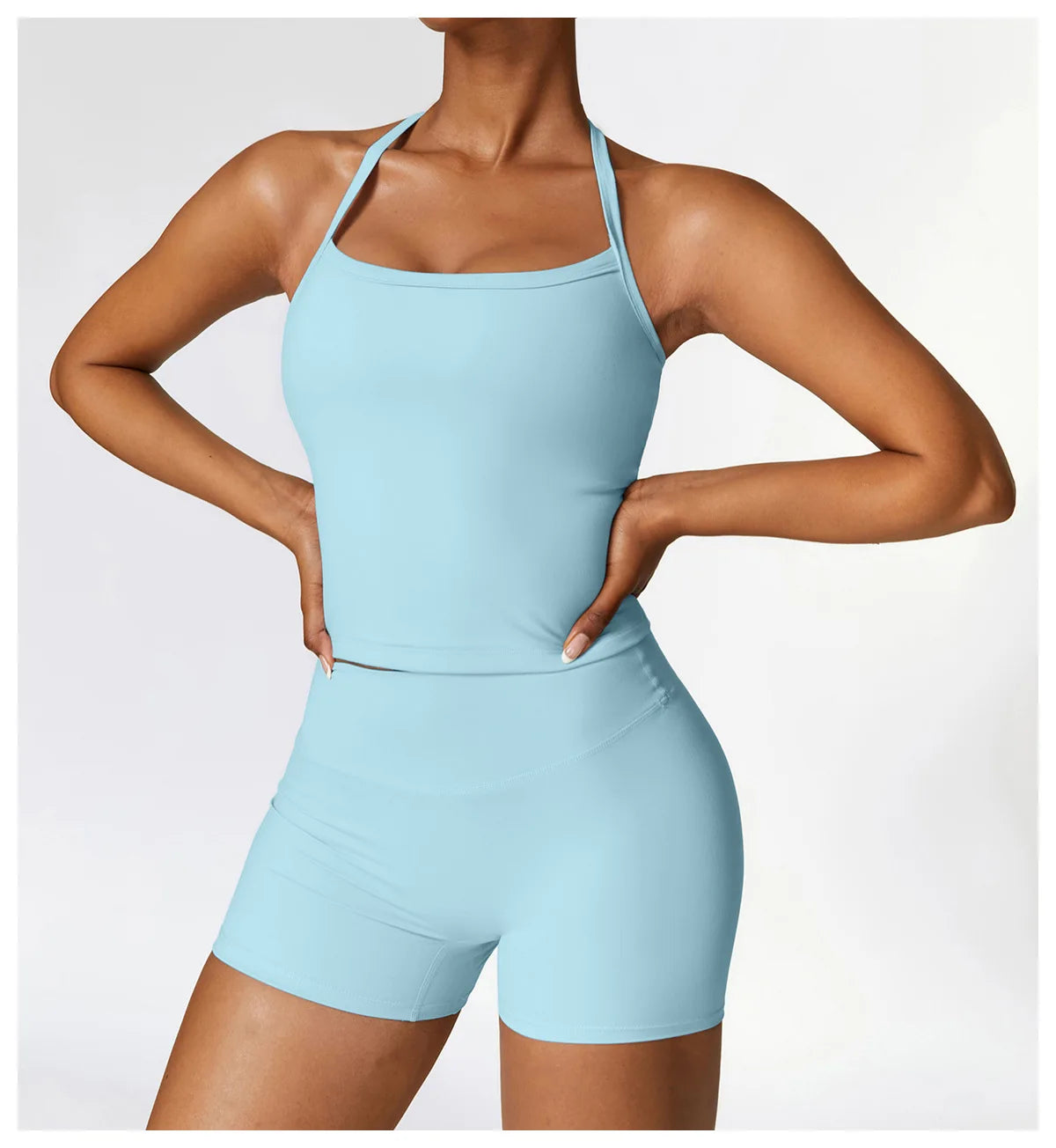 Woman in light blue cross-back sports bra and shorts, showcasing stylish activewear for workouts.