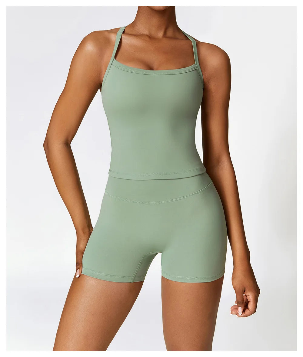 Woman modeling a light green cross-back sports bra and matching shorts, showcasing stylish athletic wear for active lifestyles.