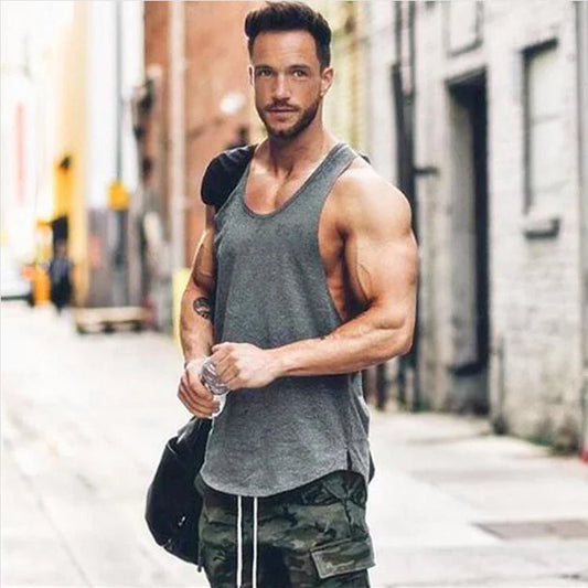 Man wearing a gray sleeveless t-shirt and camo shorts, holding a water bottle in an urban setting.