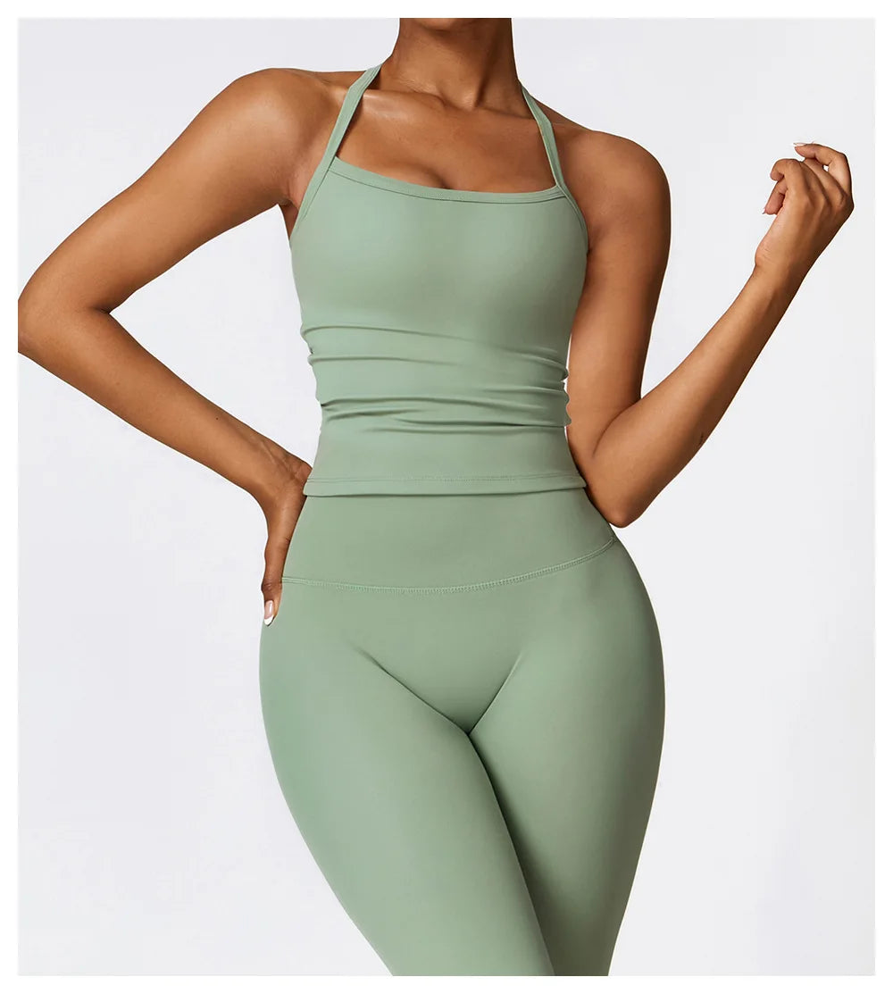 Female model wearing a light green cross-back sports bra and matching leggings, showcasing stylish athletic wear.