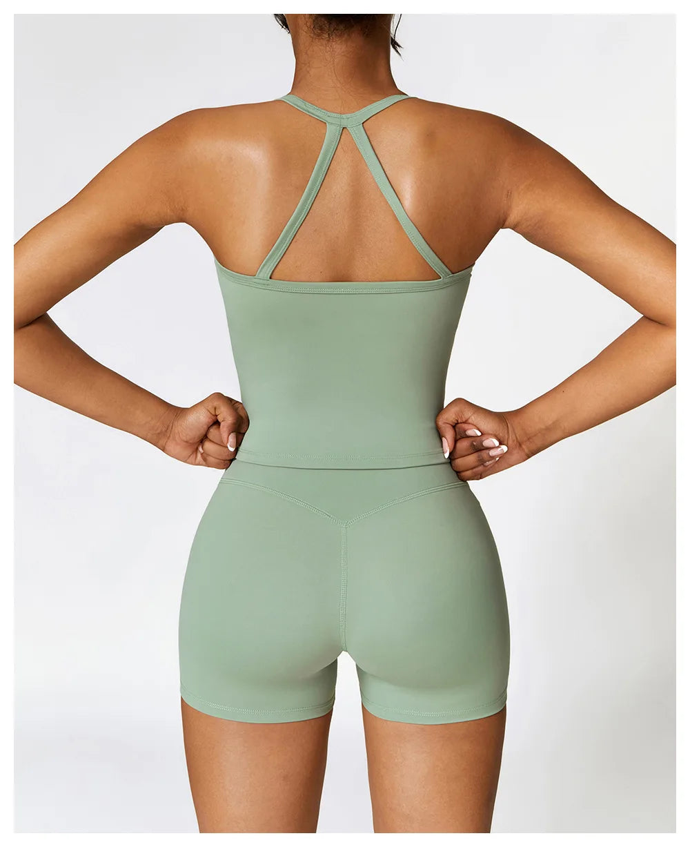 Back view of a woman in a green cross-back sports bra and shorts, showcasing stylish fitness apparel.