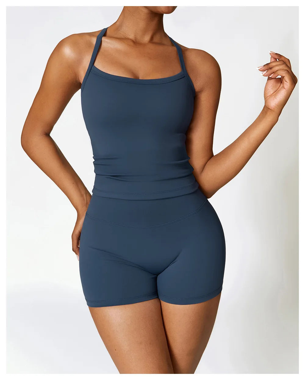 Woman wearing a stylish dark blue athletic outfit featuring a fitted tank top and shorts.