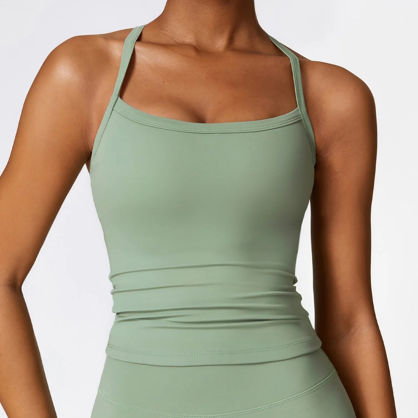 Close-up of a woman wearing a green cross back sports bra, showcasing its sleek design and supportive fit.